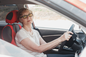 Naklejka premium The elderly woman is driving the car