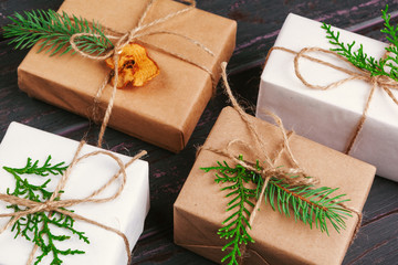 Christmas composition. Christmas gift, knitted blanket, pine cones, fir branches on wooden background.