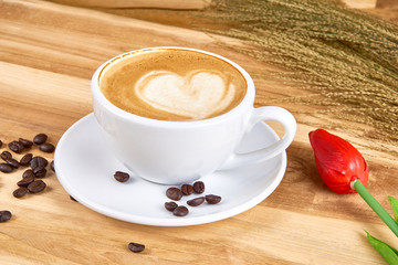 Latte art and cappuccino with hearts made from milk on the wood table with roasting coffee beans. Beverage and breakfast menu with hot coffee at the cafe shop. A cup of capuccino art.