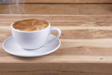 Hot cappuccino or latte art coffee. A cup of coffee on the wooden table with roasted beans. Morning breakfast with coffee. Hearts shape created by pouring steamed milk.