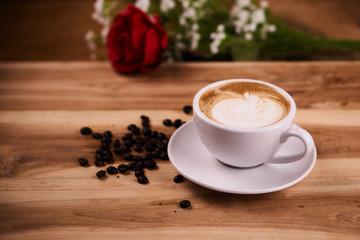 Cappuccino or latte art coffee. Free hand pouring some foam of milk on top. A white ceramic cup on the wood table with some coffee beans. The best food and drink in the world. Fresh energy everyday.