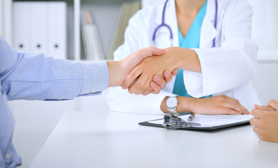 Doctor and patient shaking hands. Family couple at medical exam, just hands at the table. Medicine concept