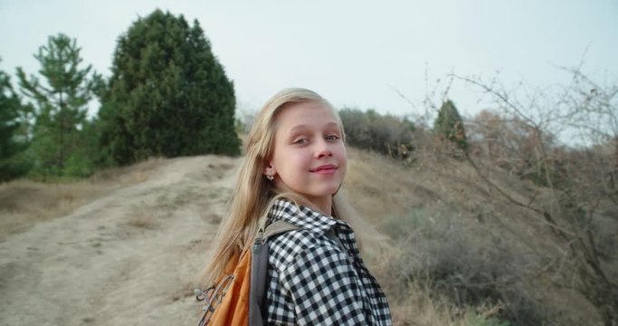 A young girl running on the mountain. In special equipment for a hike and a backpack. Her hair is fluttering in the wind. 4K slow motion video.