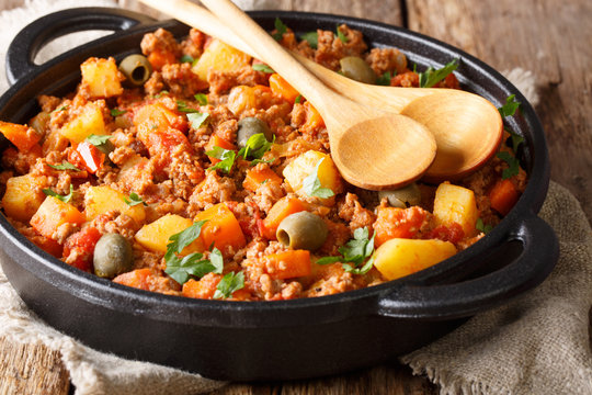 Picadillo is a popular Latin American meal cooked from ground beef with vegetables, spices close-up in a pan. horizontal
