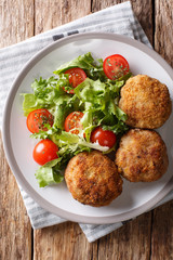 Karbonader Breaded Pork Patty Recipe with fresh vegetable salad close-up on a plate. Vertical top view