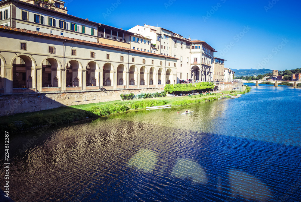 Wall mural panoramic view of arno river, vasari corridor and reflection stone medieval bridge ponte vecchio, fl