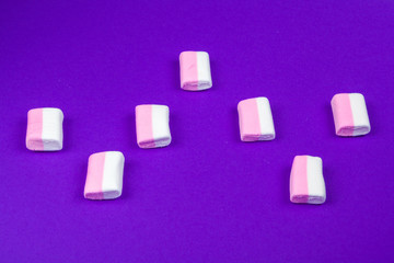 marshmallow laid out on violet paper background.