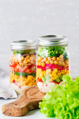 Fototapeta na wymiar Jars with layering vegan salad for healthy lunch with place for text. The concept of fitness and vegetarian food.