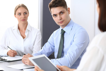 Obraz premium Group of business people or lawyers discussing terms of transaction in office. Colleagues working all together. Focus on young businessman. Meeting and teamwork concept