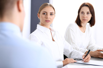 Obraz premium Group of business people or lawyers discussing terms of transaction in office. Colleagues working all together. Focus at blonde woman. Meeting and teamwork concept