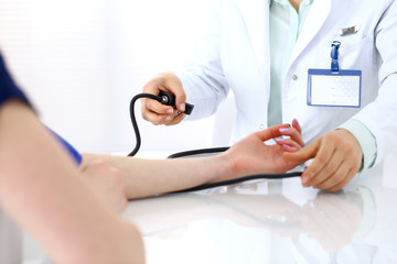 Doctor woman checking blood pressure of female patient, close-up. Cardiology in medicine  and health care concept