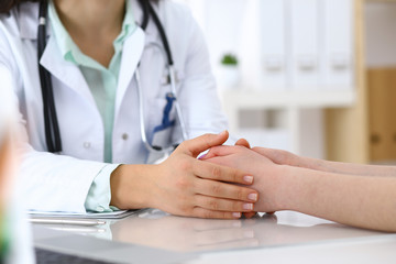 Hand of a doctor woman reassuring to female patient, close-up. Medical ethics and trust concept