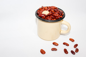 Iron light yellow mug with red and one white beans on white background