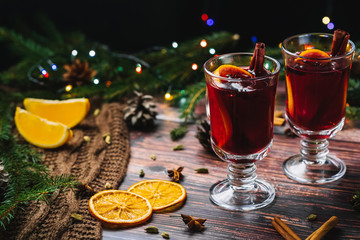 Two glasses of Christmas mulled wine with spices and orange slices on a wooden rustic table. A traditional drink for the winter holidays