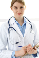 Doctor woman  using clipboard with medical record form while  standing near window in clinic or hospital. Medicine and healthcare concept. Physician at work