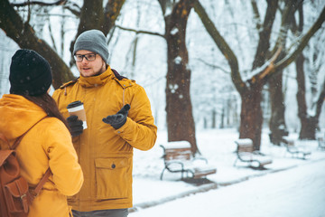 couple talking in city park man flirting with woman drinking coffee to go to warm up in winter snowed day