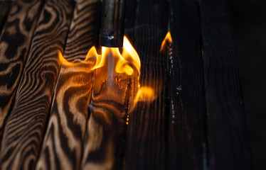 Fototapeta na wymiar Charred wooden planks and fire. Background, texture. Flame. Wood processing.