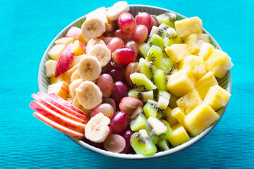 Bowl of fresh and delicious fruit salad with turquoise background
