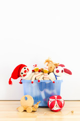 Cute and funny vintage children toys in a blue plastic box in front of a white wall. Assortment...