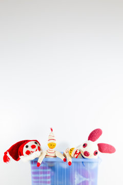 Cute and funny vintage children toys in a blue plastic box in front of a white wall. Assortment consists of a clown, a bunny and puppets.