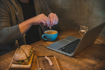 Fototapeta na wymiar man hands working on laptop in cafe eating sandwich drinking coffee