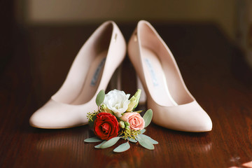 wedding accessories bouquet red, white and pink flowers for groom and beige shoes on dark wooden background