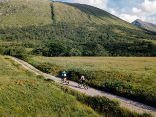 Obraz premium Couple cycling down a road in the Scottish Highlands