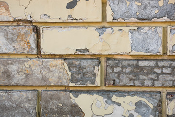 The texture of a brick wall with fallen yellow plaster
