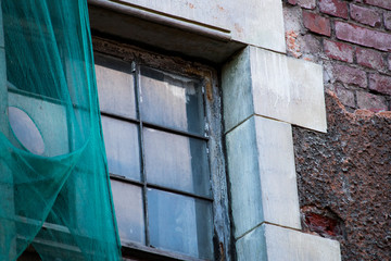 Glass window of an old building with a green safety mesh