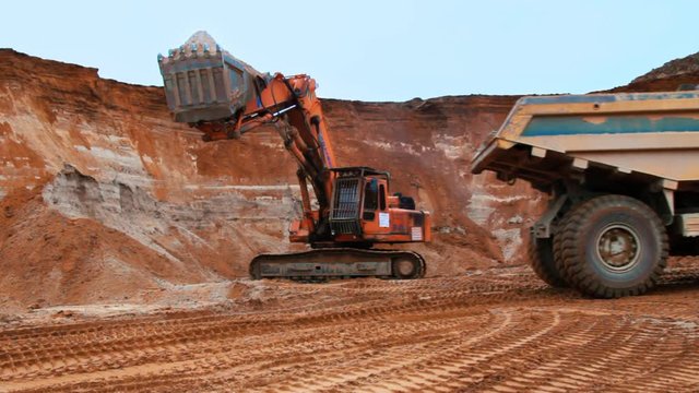 Excavator loading sand into tipper truck. Caterpillar excavator digging soil