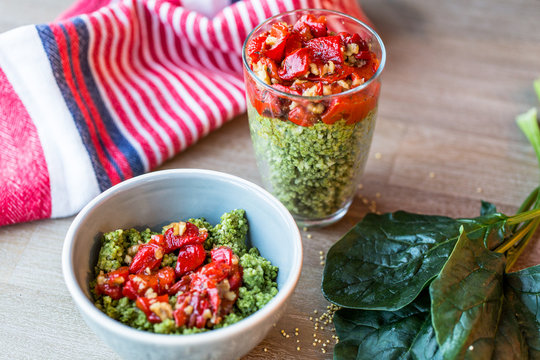 Naklejki Green millet with roasted pepper in a glass and in a a gray bowl. Spinach leaves and gggggg striped kitchen towel