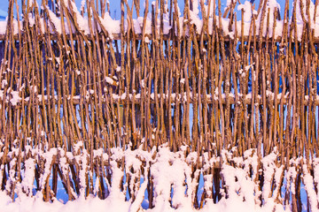 Wicker fence covered with snow texture. Rural area