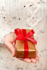 Woman holding a gift box tied with red ribbon in the hand.