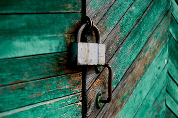 Old green door or wall of a wooden house in rustic style, with peeling paint. On the door hangs an...