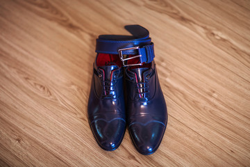 Men's shoes and belt dark blue, wedding accessories, morning groom on a brown wooden background