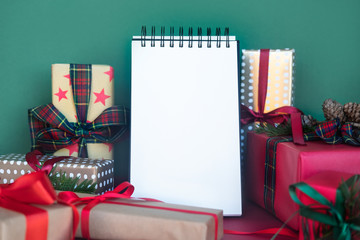 Christmas background with gift boxes and blank notebook, copy space. Template for new year goals.