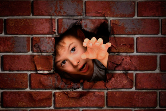 Portrait Of A Boy Peeking Out Of A Hole In A Brick Wall