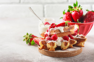 Belgian waffles with creem and raspberries and strawberries.