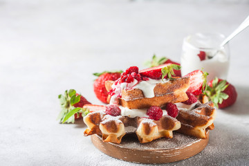 Belgian waffles with creem and raspberries and strawberries.