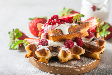 Belgian waffles with creem and raspberries and strawberries.