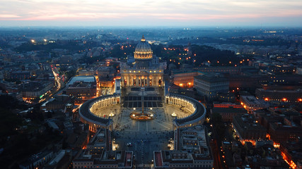 Aerial drone night view of Saint Peter's square in front of world's largest church - Papal Basilica of St. Peter's, Vatican -an elliptical esplanade created in the mid seventeenth century, Rome, Italy