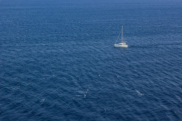 summer holidays concept of sea waves surface and small white yacht from above aerial shot, copy space 