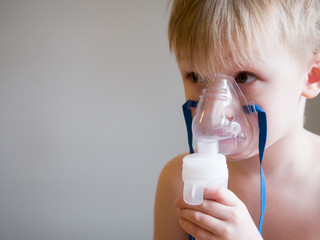 Child making inhalation with mask on his face. Asthma problems concept