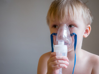 Child making inhalation with mask on his face. Asthma problems concept