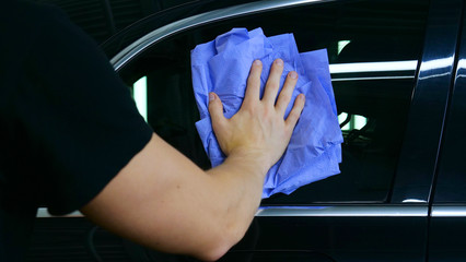 Professional car washer wipes and dries window after car washing service. Concept from: Reading...