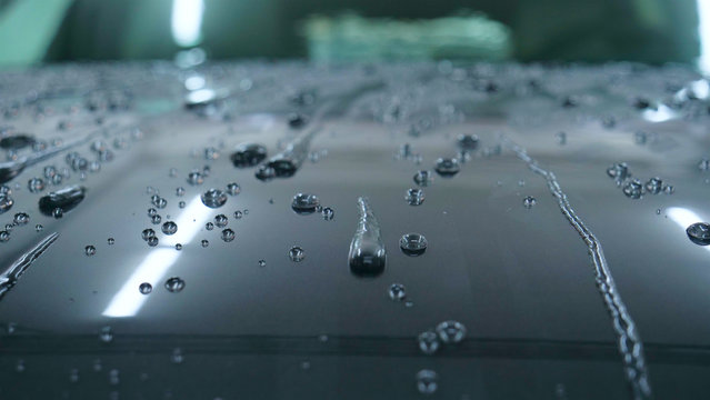 At the car wash, after washing, water drops and wax flow down the windows. Concept of: Window cleaning, Special Cleaning products, Professional work.