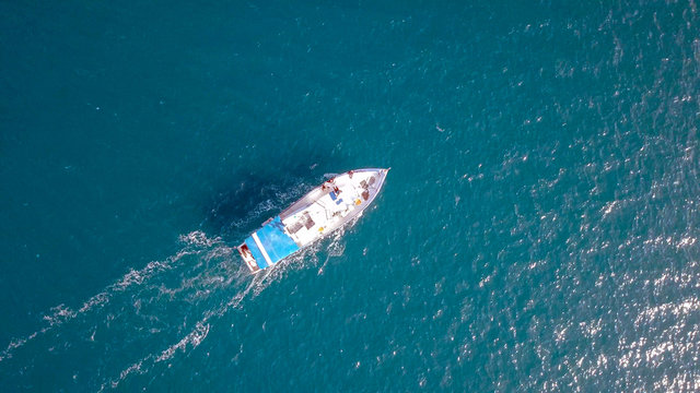 Aerial image of a small fishing boat roaring along The Mediterranean sea
