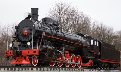 Front side view of old classic black soviet steam locomotive with red star on front
