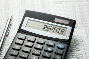 Сalculator with the inscription on the REPAIR display on the paper tables. Home or car repair