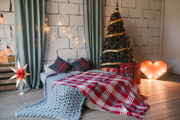 coziness, comfort, interior and holidays concept - cozy white loft bedroom with bed and christmas...